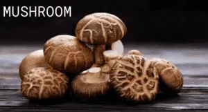 Top Foods That Increase Uric Acid & Effect Your Health: Try Their Alternatives 5 A cluster of fresh, brown shiitake mushrooms on a wooden surface, with the word "MUSHROOM" prominently displayed in white.