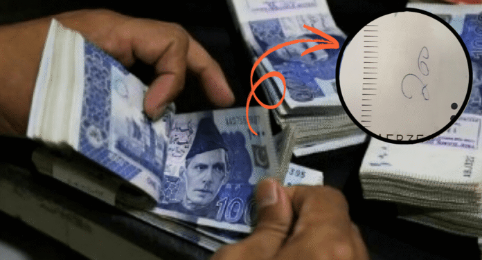 A person counts stacks of currency notes, while an inset shows a close-up of a handwritten number '26' on a piece of paper.