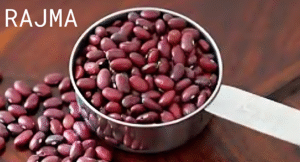 Top Foods That Increase Uric Acid & Effect Your Health: Try Their Alternatives 1 A silver measuring cup filled with red kidney beans (rajma) on a wooden surface, with some beans scattered around.