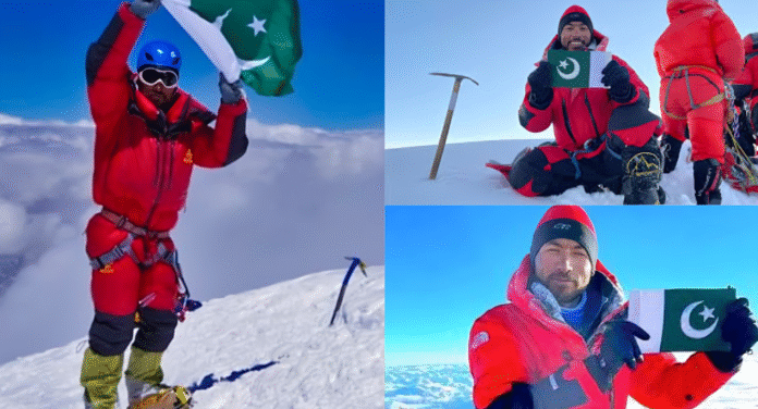 Mountaineer Sirbaz Khan celebrates at the summit, proudly holding the Pakistani flag against a backdrop of clouds and snow-covered peaks.