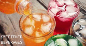 Top Foods That Increase Uric Acid & Effect Your Health: Try Their Alternatives 6 A vibrant display of sweetened beverages in colorful glasses with ice; orange, red, green, and clear drinks arranged on a wooden table.