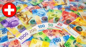 Colorful Swiss franc banknotes featuring various designs and denominations, scattered across a surface with a Swiss flag emblem.