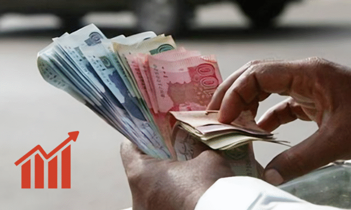 A hand holding a stack of colorful banknotes next to a rising graph icon, symbolizing financial growth or increment.