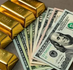 A stack of gold bars beside an arrangement of various U.S. dollar bills, highlighting wealth and financial investment. A stack of gold bars beside an arrangement of various U.S. dollar bills, highlighting wealth and financial investment.
