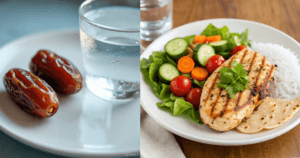 A glass of water beside two dates on a plate, accompanied by a meal of grilled chicken, rice, and a fresh vegetable salad.